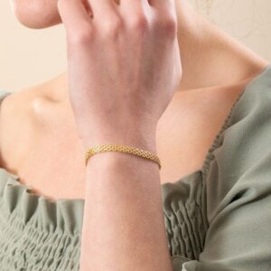 Ett elegant bismarckarmband i guld på en kvinnas handled.