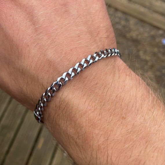 Silverfärgat pansararmband runt en mans handled.