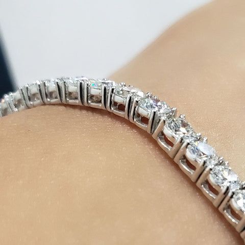 Närbild av ett gnistrande tennisarmband i silver eller vitguld på en handled.