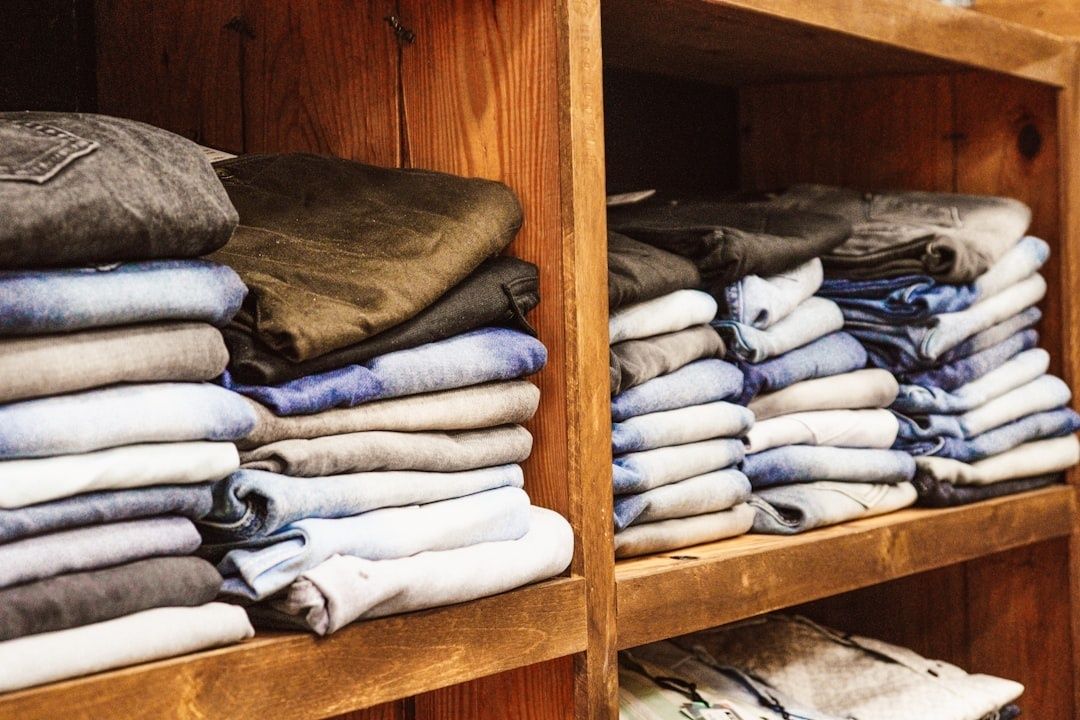 Vikta jeans och neutrala plagg staplade i en träförvaring